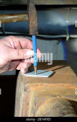 Workshop scene with a human hand holding a center punch that s used for marking a piece of metal. Stock Photo