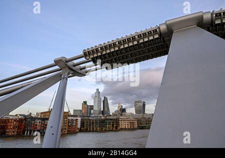 City of London, UK with view over the River Thames framed by the Millennium Bridge. Cityscape of the business district with clouds. London 2020.