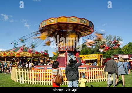 Basingstoke, UK - September 1, 2019:  Spectators watching people enjoying the vintage Chair O Plane ride at Carter's Steam Fair on a sunny summer day Stock Photo