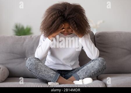 Depressed upset african american teen girl feeling hurt sitting alone Stock Photo