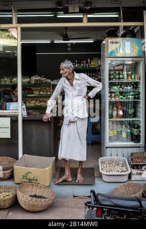 And old man standing in a store opening in India. Stock Photo