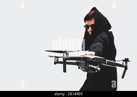 female spy in black clothes and round glasses with a drone isolated on gray background Stock Photo