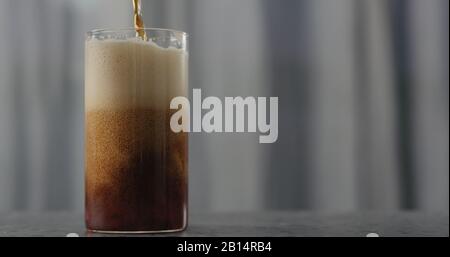 dark beer pour into glass on concrete countertop, wide photo Stock Photo