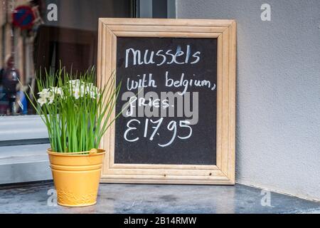 25 September 2018: Bruges, Belgium - Sign outside restaurant in Bruges advertising famous Belgian meal of mussels with fries, moules avec frites. Stock Photo