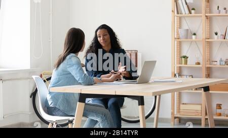 Young mixed race coworkers discussing working issues together at workplace. Stock Photo