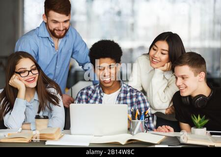 Happy students watching tutorial videos on laptop Stock Photo