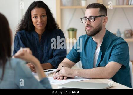 Focused mixed race hr managers listening to young job applicant. Stock Photo