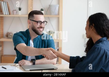 Smiling hr manager shaking hands with african american job applicant. Stock Photo