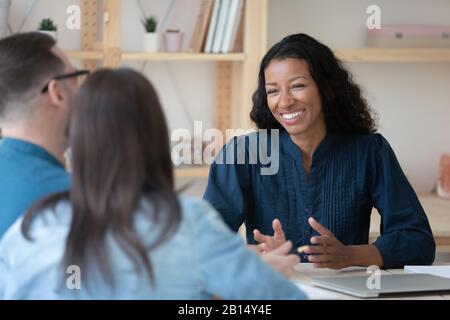 Smiling professional african american financial advisor talking to clients. Stock Photo