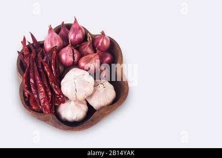 Thai spices on wooden plate. Dried chilies, shallots and garlic isolate on white background with clipping path Stock Photo