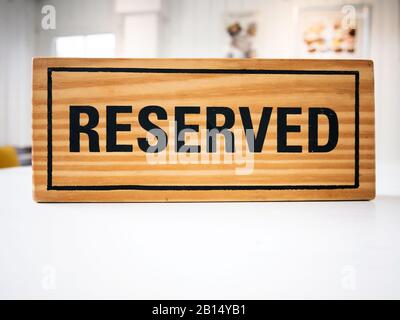 Reservation seat at restaurant for dating on celebrate day concept. Restaurant with reserved wooden sign on white table with cafe decorate places sett Stock Photo
