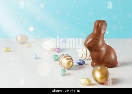 Golden Easter eggs and chocolate Easter bunny over blue background. Happy Easter time. Easter greeting card background. Stock Photo