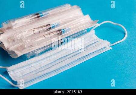 Syringes in a package and a medical mask on a blue background.The concept of prevention of viral diseases. Stock Photo