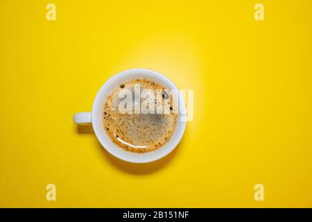 White coffee Cup with foam on a bright yellow background top view, minimalism concept Stock Photo