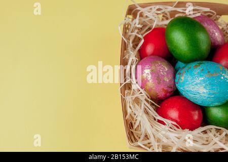 Happy Easter eggs yellow background. Golden shine decorated eggs in basket, for greeting card, promotion, poster. Copy space Stock Photo