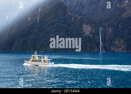 The morning sun sends shafts of light into Milford Sound, New Zealand to delight those on an early cruise. Stock Photo