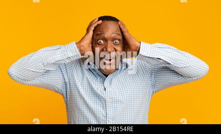 Portrait of excited mature african man holding his head Stock Photo