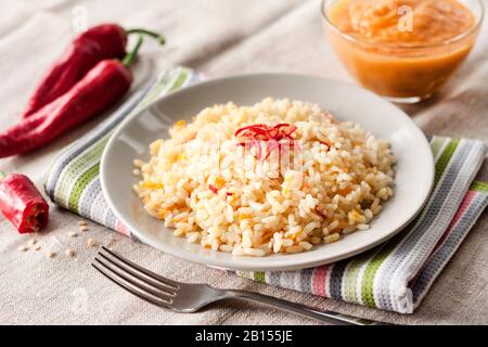 Spicy parboiled rice with carrots, yellow zucchini and chili peppers on a gray plate Stock Photo