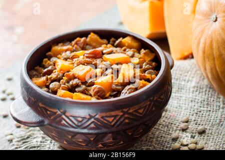 Homemade spicy curry with green lentils, pumpkin and raisins in rustic ceramic bowl Stock Photo