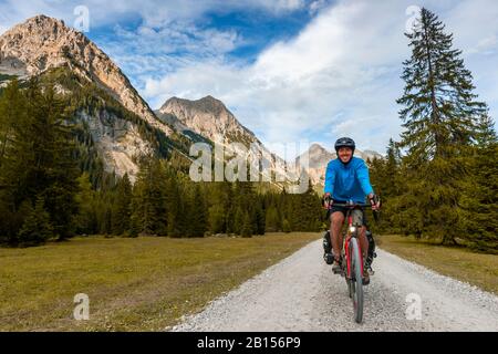 Cyclist, mountain biker bikes on gravel road, Karwendeltal, way to the Karwendelhaus, Tyrol, Austria Stock Photo