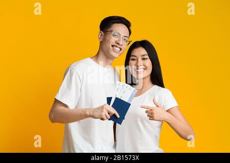 Happy young asian couple holding passports and tickets Stock Photo