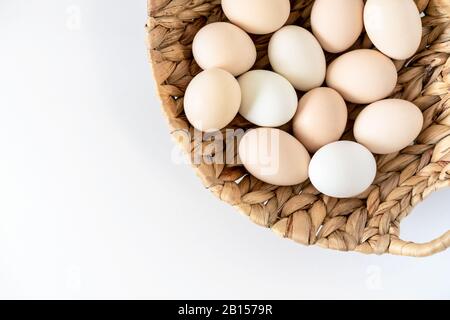 Fresh raw farm organic chiken eggs in a basket on whita background. Natural healthy food and organic farming, easter concept. Stock Photo