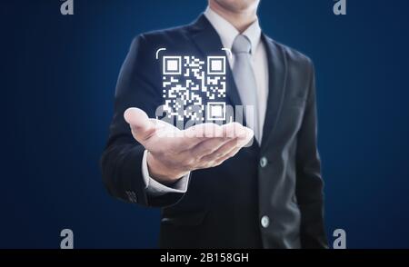 Businessman holding QR code on hand. QR code scanning payment and verification technology Stock Photo