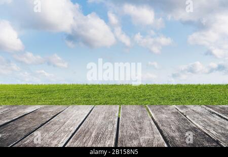 Green grass, blue sky and white clouds with wooden floor backgrounds Stock Photo