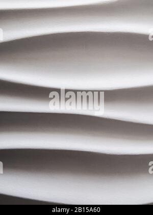 Abstract background formed by smooth wavy lines of gypsum on the wall. The difference of lights and shadows on a relief surface. Stock Photo