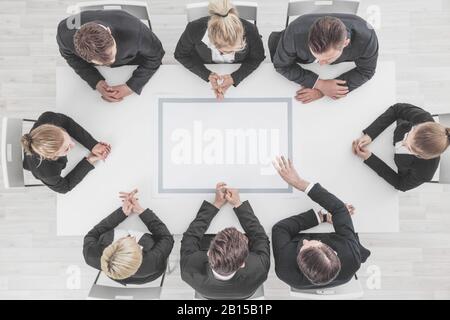 Business people sitting around blank frame on table, business man pointing to blank copy space in the middle Stock Photo