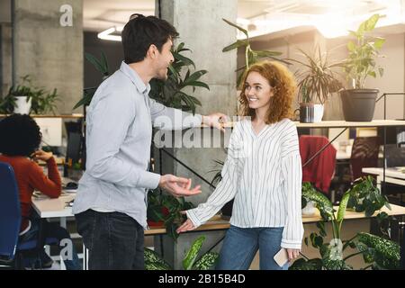 Young man and woman chatting during working time in office Stock Photo
