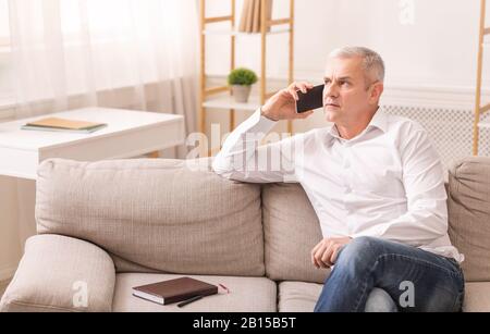 Senior man talking on mobile phone at his home Stock Photo