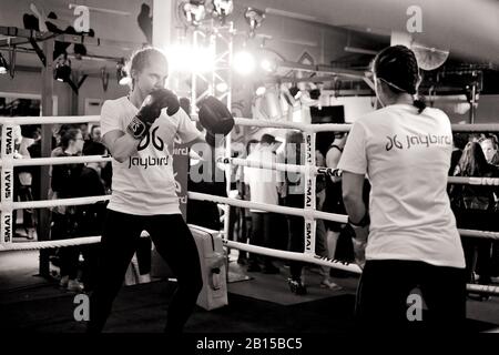 Two female athletes sparring and training in a boxing ring, woman and sports, demonstration with people milling in the background. Kings Cross, Sydney Stock Photo