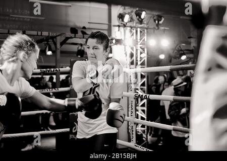 Two women athletes sparring and training in a boxing ring, sports demonstration with people milling in the background. Kings Cross, Sydney Stock Photo