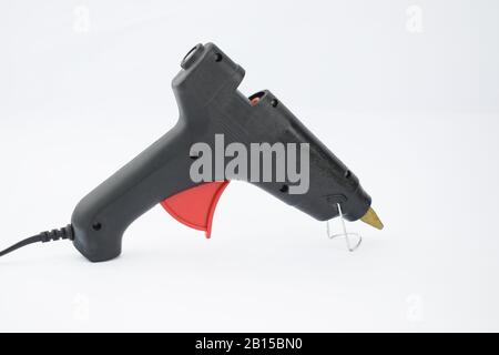 Close up picture of a black glue gun with a red trigger before an isolated white background Stock Photo