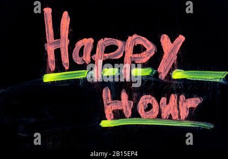 Happy hour written in pink on black chalkboard with chalk Stock Photo