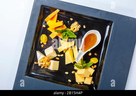 Cheese plate - pieces of different types of cheese with nuts and honey. On white background. The view from the top. Stock Photo