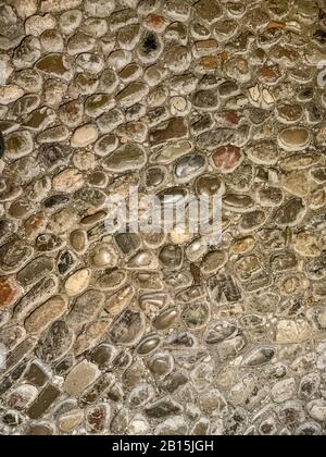 Ground of river pebble stones. Old, weathered and scuffed cobblestones, made of round river stones of different sizes, grouted with mortar. Closeup. Stock Photo
