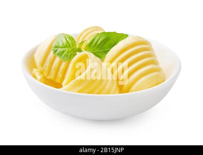 Butter curls or butter rolls in white bowl with fresh basil leaves isolated on white background. Stock Photo
