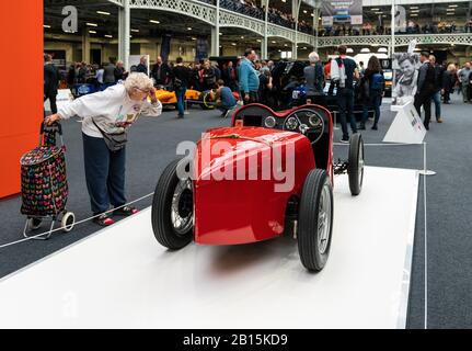 22 Feb 2020 - London, UK. Old woman curiously checking on restored 1929 Austin Ulster model at Classic Car Show. Stock Photo