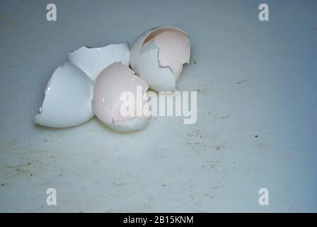 Close up of two cracked eggshells on a well used cutting board Stock Photo