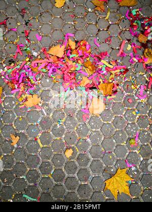 Multicoloured tinsel mixed with the autumn yellow leaves on the pavement,abstract colourful background Stock Photo