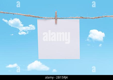 Blank Paper, hanging on rope by pin against blue Background, concept, office Stock Photo