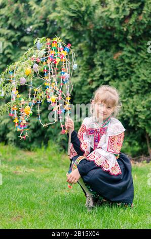 girl in embroided colorful traditional slovakian costume during Easter holiday with basket full of eggs in village Stock Photo