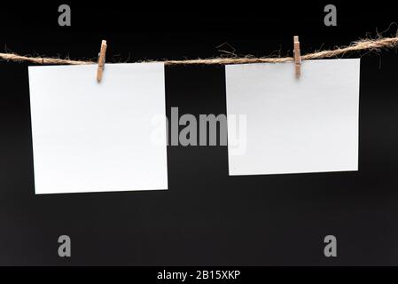 Blank Paper, hanging on rope by pin against black background, concept, office Stock Photo