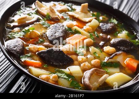 Spicy diet soup with mushrooms, vegetables and chickpeas closeup in a bowl on the table. horizontal Stock Photo