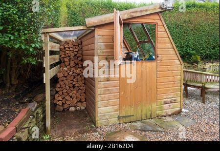 Garden shed with covered log pile Stock Photo