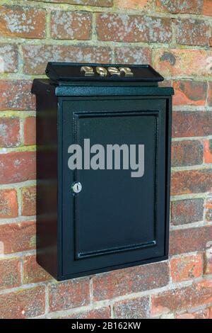 Vintage black post box or letterbox on a brick wall in England, UK Stock Photo
