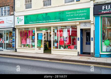 Trussell Trust food bank charity shop displaying donated clothing in the windows with entrance door open Stock Photo