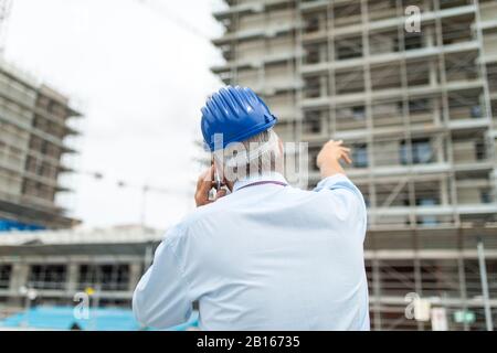 Architect manager talking on the cellphone and pointing his finger to his construction site Stock Photo